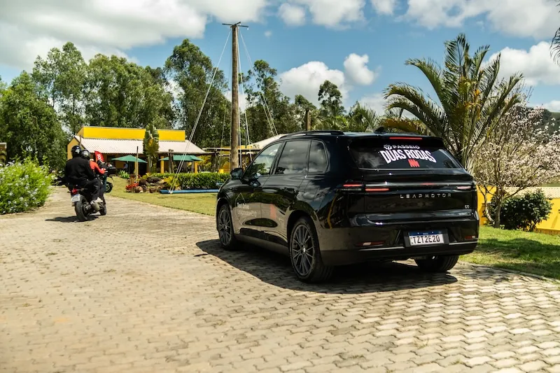 Uma moto e o carro de apoio com o adesivo do Passeio Duas Rodas, numa parada do passeio
